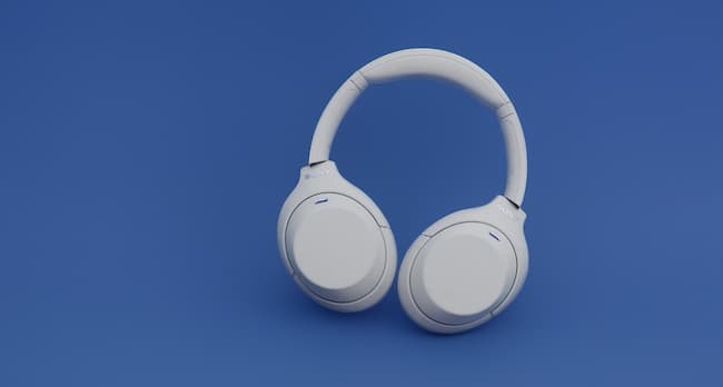 A pair of white wireless headphones on a blue surface