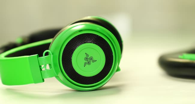 A pair of parrot green Razer Kraken X gaming headphones on a white surface