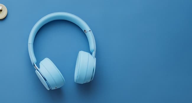 A pair of white on-ear headphones on a blue background